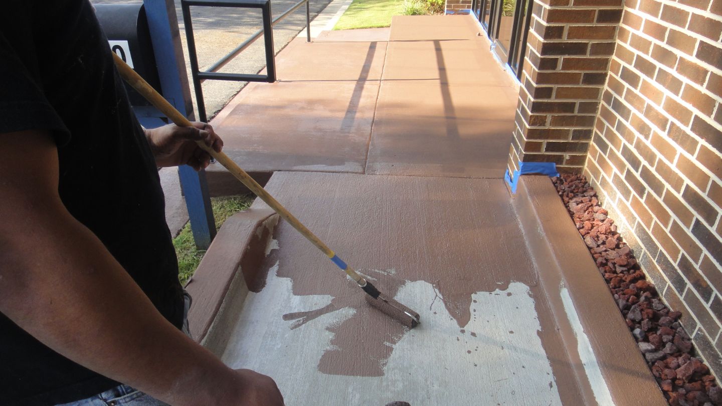 Person Painting a Concrete Sidewalk